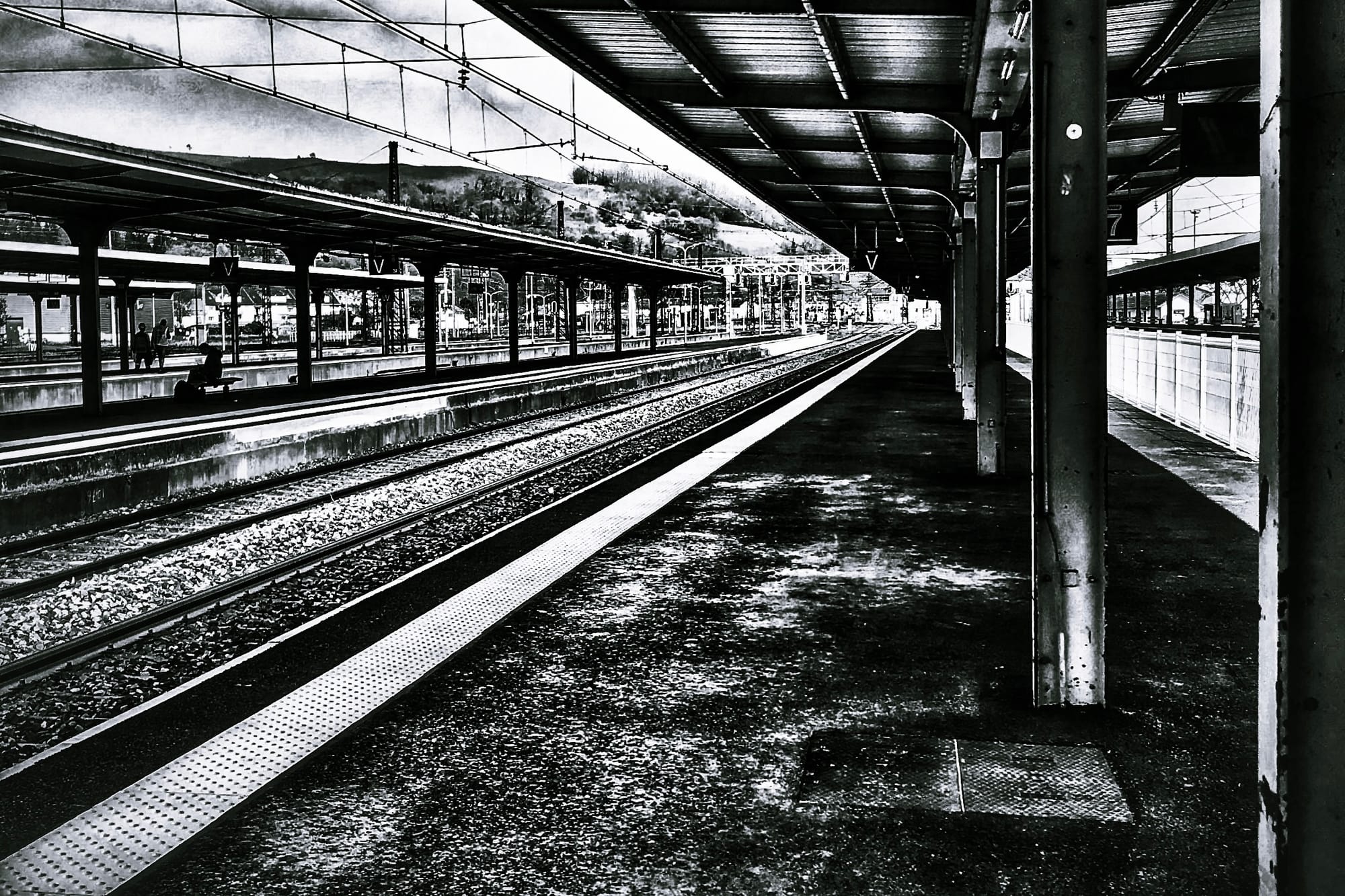 Photographie monochrome des rails et des quais de la gare de Lourdes.